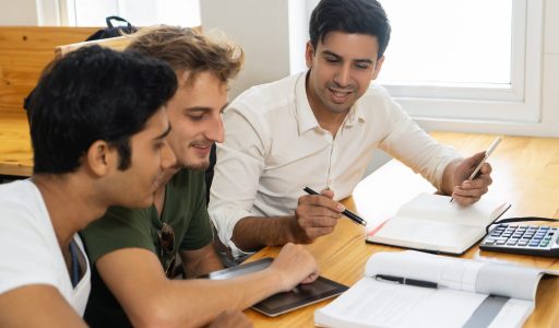 Young teacher telling two students about corporate budgeting. Two young guys in casual tshirts listening to confident man in white shirt. Business school concept